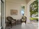 Charming porch featuring comfortable wicker seating, decorative wall art, and a view of the well-manicured front yard at 13190 Se 93Rd Cir, Summerfield, FL 34491