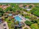 Aerial view of a sparkling community pool with lounge chairs, palm trees, and vibrant landscaping at 132 Palermo Pl, The Villages, FL 32159