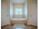 Clean bathroom featuring garden tub and tile surround, framed by doors on each side at 15141 Farm Rd, Groveland, FL 34736