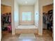 Relaxing tub area with glass block window, flanked by two walk-in closets at 15141 Farm Rd, Groveland, FL 34736