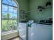 Well-lit laundry room with large window and green walls, perfect for chores at 15141 Farm Rd, Groveland, FL 34736