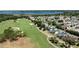 Aerial view of a golf course, lake, and neighborhood featuring mature trees and landscaping at 1667 Osprey Ave, The Villages, FL 32162