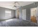 Carpeted bedroom features a ceiling fan, gray walls and a large window at 1667 Osprey Ave, The Villages, FL 32162