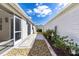 Exterior shot featuring the screened-in lanai, and gravel landscaping and walkway, with blue skies and lush greenery at 1667 Osprey Ave, The Villages, FL 32162