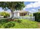 Well-maintained home with a white picket fence, lush green lawn, mature shade tree, and tidy landscaping at 1667 Osprey Ave, The Villages, FL 32162