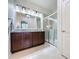 Bathroom with dual sink vanity, granite countertop, and glass-enclosed shower at 1688 Littleleaf Boxwood Loop, Mascotte, FL 34753