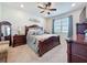 Elegant bedroom featuring a decorative ceiling fan, neutral carpet, and refined wood furniture at 1688 Littleleaf Boxwood Loop, Mascotte, FL 34753