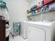 Bright laundry room with washer, dryer, shelving and storage, plus white tile flooring at 1688 Littleleaf Boxwood Loop, Mascotte, FL 34753