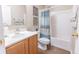 Well-lit bathroom featuring a shower and bathtub combo with stylish curtain and wooden vanity at 1704 Hoofprint Court, Fruitland Park, FL 34731