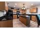 Spacious kitchen with wood cabinets, black countertops, and a center island with a sink at 1704 Hoofprint Court, Fruitland Park, FL 34731