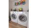 Functional laundry area featuring modern white washer and dryer with wire shelving at 1704 Hoofprint Court, Fruitland Park, FL 34731