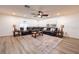 Open living room boasts a ceiling fan, wood floors, and a decorative rug beneath a leather sectional sofa at 1704 Hoofprint Court, Fruitland Park, FL 34731