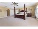 Bright main bedroom featuring a four-poster bed, plush carpeting, and natural light from multiple windows at 1704 Hoofprint Court, Fruitland Park, FL 34731