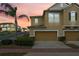 Inviting townhome featuring a two-car garage, meticulously landscaped yard, and a lush palm tree at 17519 Promenade Dr, Clermont, FL 34711