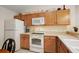 Galley kitchen area featuring wood cabinets, white appliances, and ample counter space at 1833 Endsley Ct, The Villages, FL 32162