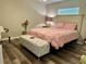 Cozy bedroom features a bed with pink bedding and an ottoman with decorative buttons at 2071 Westchester Way, The Villages, FL 32162