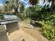 Grill on concrete patio with lush landscaping and pond at 2071 Westchester Way, The Villages, FL 32162