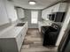 Galley kitchen featuring white cabinets, stainless appliances, and wood-look floors at 2107 Hollywood Ave, Eustis, FL 32726