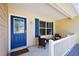 Inviting front porch with a blue door, cozy seating, and stylish decor, offering a warm welcome at 2290 Due West Dr, The Villages, FL 32162
