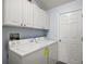 Functional laundry room with a washer, dryer, and ample storage space in white cabinets at 2290 Due West Dr, The Villages, FL 32162