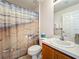 Well-lit bathroom features a single sink and beach themed shower curtain at 25044 Cranes Roost Cir, Leesburg, FL 34748