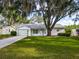 Charming single-story home with a well-manicured lawn, mature trees, and attached garage at 25540 Belle Helene, Leesburg, FL 34748