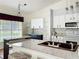 Bright kitchen features granite countertops, stainless steel appliances, tile backsplash, and modern lighting at 25540 Belle Helene, Leesburg, FL 34748
