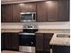 Well-equipped kitchen with granite countertops, stainless steel appliances and dark wood cabinets at 27 Perch Dr, Kissimmee, FL 34759