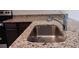 Close-up of stainless steel kitchen sink with granite countertops and chrome faucet fixture at 27 Perch Dr, Kissimmee, FL 34759
