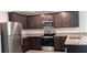 Modern kitchen featuring stainless steel appliances, granite countertops, and dark wood cabinets at 27 Perch Dr, Kissimmee, FL 34759