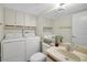 Bright bathroom features white cabinets, sink, toilet and washer/dryer at 2934 Tangerine Ct, Leesburg, FL 34748