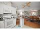 Charming kitchen featuring white appliances and cabinets with a view of the dining and living areas at 3209 Manatee Rd, Tavares, FL 32778