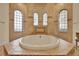 Luxurious bathroom with a large soaking tub, tile surround, and arched windows at 39705 Grove Hts, Lady Lake, FL 32159