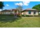 Charming single-story home featuring a well-manicured lawn and a welcoming front entrance with red door at 39705 Grove Hts, Lady Lake, FL 32159