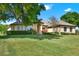 Home's front exterior with a green lawn, tidy shrubbery, and mature trees at 39705 Grove Hts, Lady Lake, FL 32159