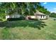 View of the front of a home with a large lawn, shrubbery, and trees casting shadows at 39705 Grove Hts, Lady Lake, FL 32159