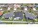 An aerial view of a neighborhood displays single-story homes, green lawns, and a charming pond at 449 Gilson Loop, The Villages, FL 32163