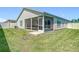 Backyard view showcasing a screened patio, lawn, and modern home exterior at 449 Gilson Loop, The Villages, FL 32163
