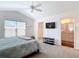 Spacious main bedroom boasts vaulted ceilings, view windows, tv, and convenient access to ensuite bathroom and walk-in closet at 449 Gilson Loop, The Villages, FL 32163