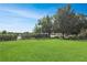 Open green backyard featuring mature trees and partial view of tennis court at 5408 Queen Victoria Dr, Leesburg, FL 34748