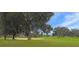 Scenic golf course view with lush green grass, mature trees, sand trap, and blue sky on a sunny day at 5408 Queen Victoria Dr, Leesburg, FL 34748