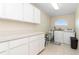 Bright laundry room with tile flooring, ample cabinet storage, countertop and a utility sink at 5408 Queen Victoria Dr, Leesburg, FL 34748