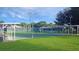 A well-maintained tennis court with covered seating areas and manicured grass at 5408 Queen Victoria Dr, Leesburg, FL 34748