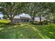 Lush backyard with mature trees and landscaping, partially obscuring the back of the house at 5557 Freeport Dr, Tavares, FL 32778