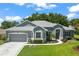 Charming single-story home with a well-manicured lawn, complemented by lush landscaping and an attached garage at 5557 Freeport Dr, Tavares, FL 32778