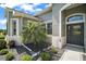Close-up of the home's entryway showcasing a well landscaped garden and a decorative front door with unique glass detailing at 5557 Freeport Dr, Tavares, FL 32778