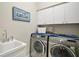 Efficient laundry room with sink, modern washer and dryer, and built-in storage at 5557 Freeport Dr, Tavares, FL 32778