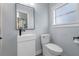 A modern half bathroom with a sleek white sink, toilet, black faucet, and black framed mirror at 602 Ross St, Leesburg, FL 34748