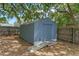 A gray outdoor shed with a ramp, surrounded by a wooden fence, offering ample storage space at 602 Ross St, Leesburg, FL 34748