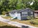 Charming single-story home with gray stucco, black shutters, a solar panel roof and mature trees at 726 S Stone St, Deland, FL 32720